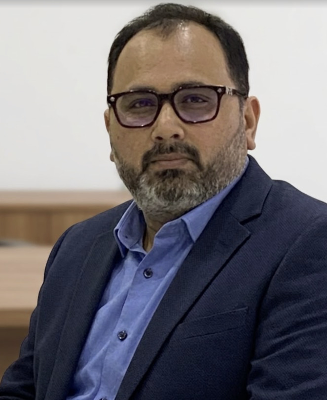Aashish Sanghvi — a bespectacled businessman in a checked blazer and blue shirt.