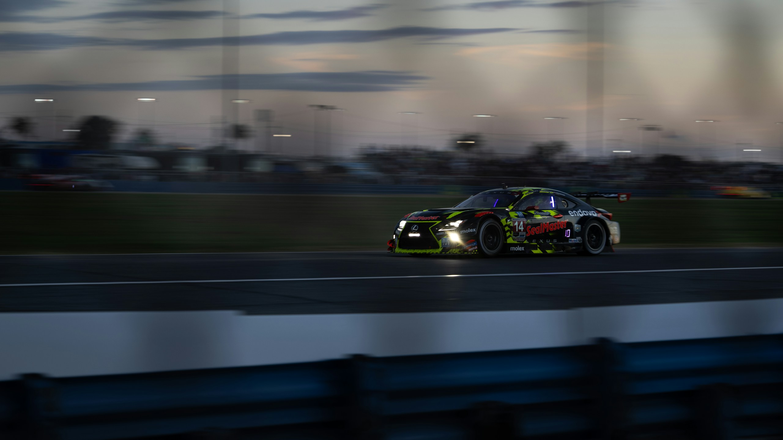 Race cars at speed on a circuit on race day.
