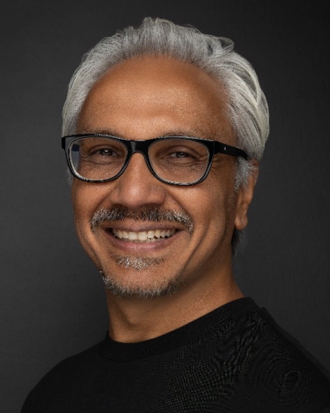 Sheetal Jain — a smiling man with grey hair and glasses in a black top.